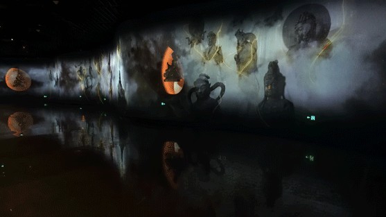 Dark panoramic exhibition space with Buddhist imagery projected across a long curved screen