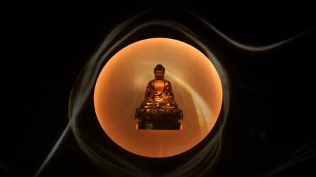 Golden seated Buddha image surrounded by flowing rings of light