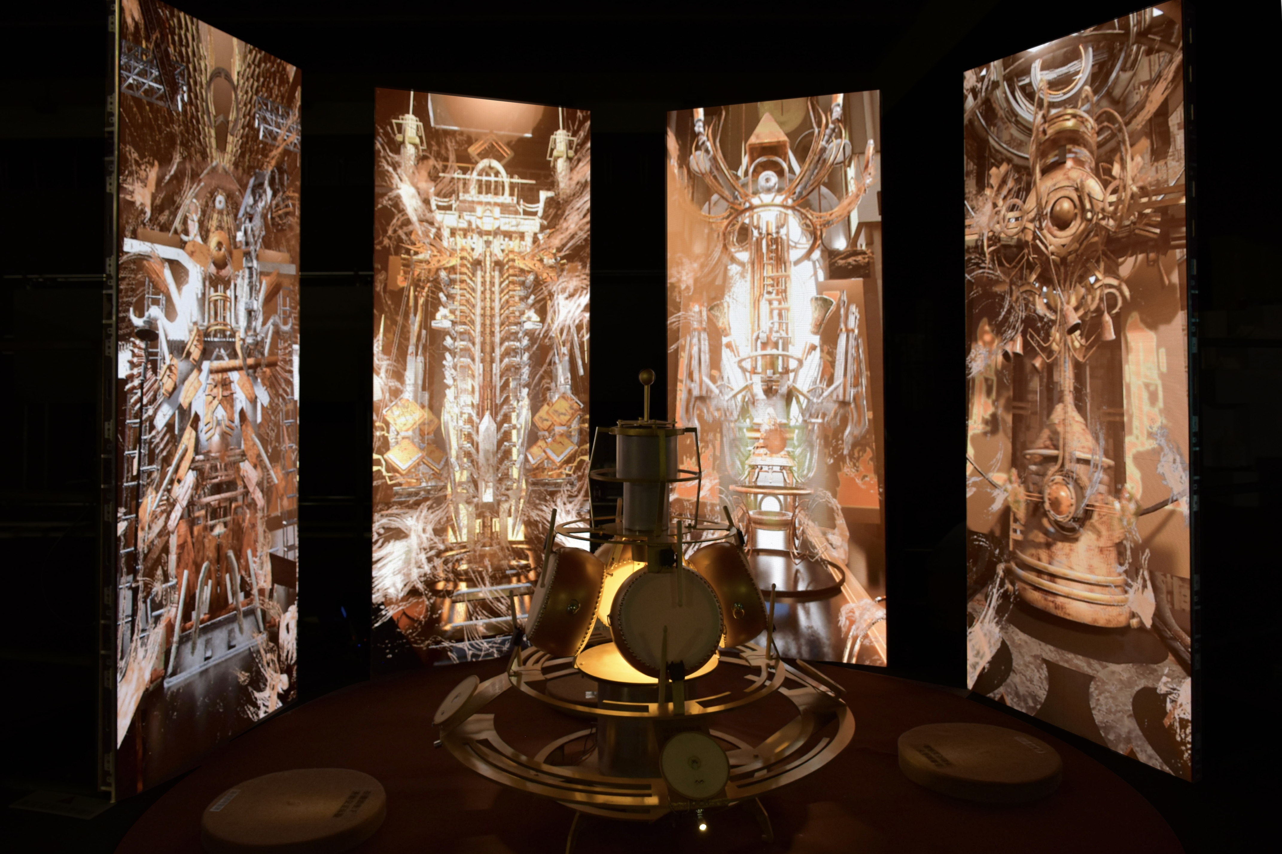Resonance installation with a circular frame drum surrounded by four illuminated projection panels